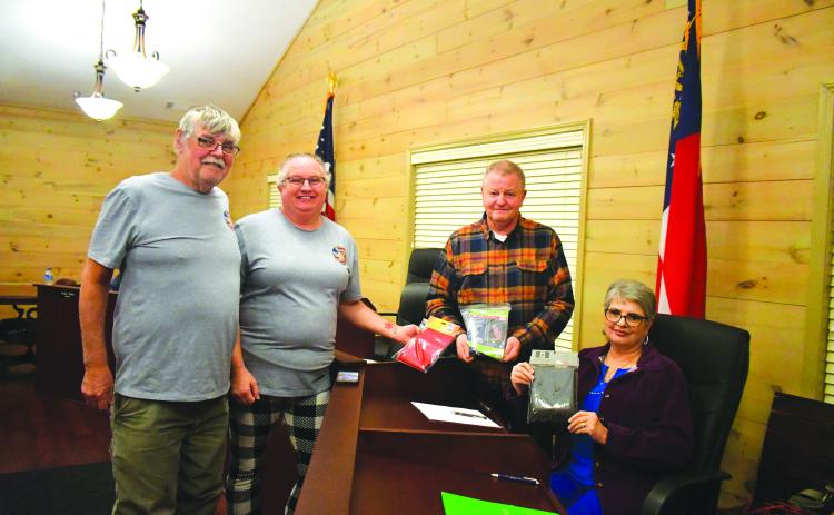 Megan Broome/The Clayton Tribune. Johnnie Robinson, president of the Board of Directors of Creating Ties that Bind, and Pam Wheeler, CEO of Creating Ties That Bind (left) present a United States flag, State of Georgia flag, and POW flag to Tiger Mayor Mike Carnes, center, and the Tiger Town Council at the Feb. 13 council meeting. Also pictured is Tiger Town Council member Karen Lovell.