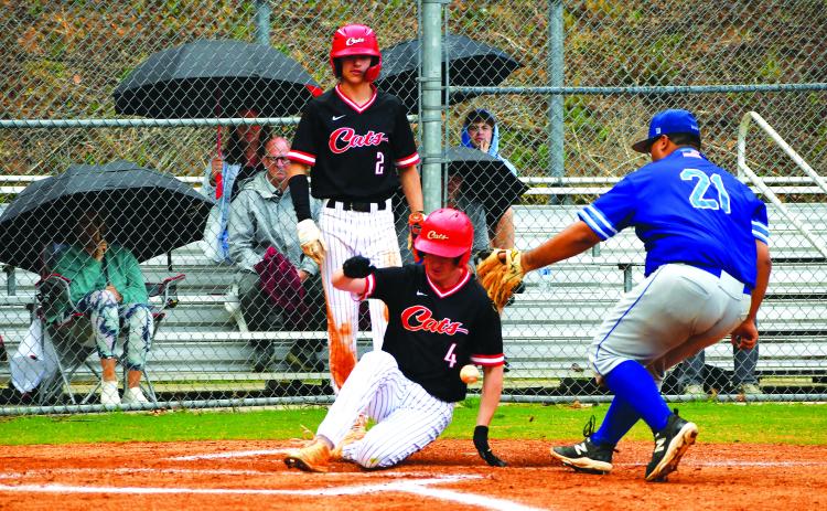 Luke Morey/The Clayton Tribune. With freshman Ty Truelove looking on, Rabun County senior Nathan Thompson slides into home plate on Thursday, April 13 against Barrow Arts and Sciences Academy.