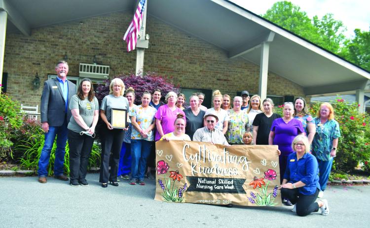 Megan Broome/The Clayton Tribune.  Nurses hold up a sign created by RCHS student Abbye Carver. Resident Ervin Chastain, who turns 100 years old in June, also enjoyed the presentation.