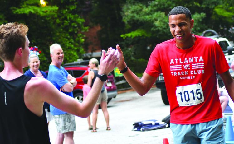 Enoch Autry/The Clayton Tribune. Alex Thomas (left) congratulates his Atlanta Track Club teammate Tristan Antg on a great 5K run at the Rabun Ramble. Thomas took first; Antg took third; and track club teammate Jack Voss took second.