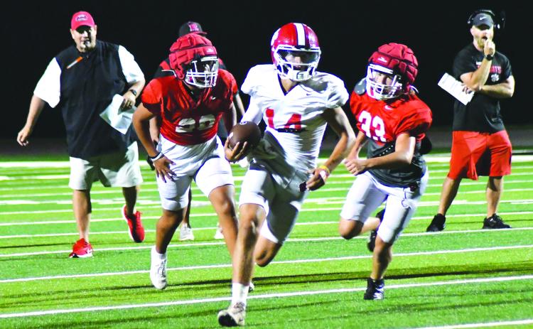 Enoch Autry/The Clayton Tribune. Sophomore starting quarterback Ty Truelove slips through the Wildcat defense for a gainer on the ground as RCHS head coach Michael Davis (left) watches in the background.