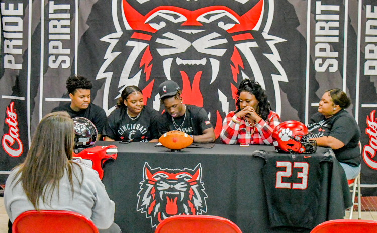 Wade Cheek/The Clayton Tribune. Rabun County Wildcat standout Willie Goodwyn signs his letter of intent to play football for the University of Cincinnati Bearcats Monday.