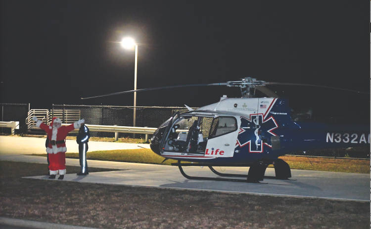 Megan Horn/The Clayton Tribune. Santa arrives at Mountain Lakes Medical Center by helicopter Dec. 14 and waves to a crowd of children jumping up and down in excitement.