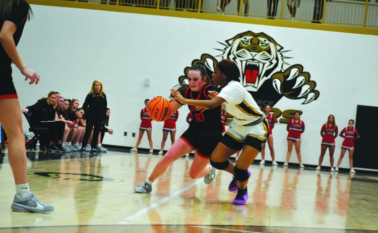 Wade Cheek/The Clayton Tribune. With Lady Cat head coach DeeDee Dillard, the RCHS players, and RCHS cheerleaders watching, senior Mili Watts makes her move to the basket against the Lady Tigers in Commerce.