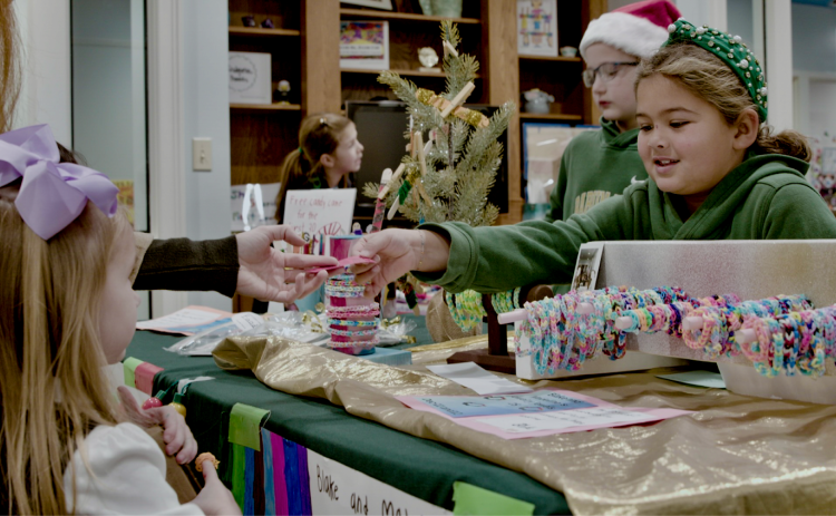 Submitted photo. Rabun Gap-Nacoochee School hosted its third annual Second Grade Marketplace on Tuesday, Dec. 12, where students learned entrepreneurship and economics while raising money for a community garden. Pictured, Blake Ruiz, Class of 2034 of Otto, N.C., interacts with a customer on market day.