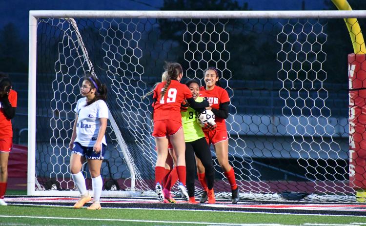 Wade Cheek/The Clayton Tribune. RCHS girl soccer players celebrate with Lady Cat goalkeeper Alesia Gonzalez after she earned a save against Elbert County on Wednesday, Feb. 28. The Lady Cats won 8-1 for their second-straight region win.