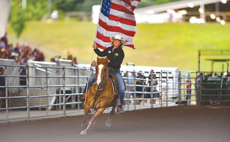 Wade Cheek/The Clayton Tribune. Jamie Ellsworth, a breakaway roper, makes her rounds with the American Flag at Rabun Arena as part of the opening ceremonies of last weekend’s Bar W Rodeo that started on Friday, July 5.