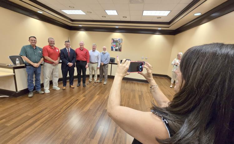 Enoch Autry/The Clayton Tribune. Anglea Cole takes a photograph of the Rabun County school board members and her husband Steven Cole (center) after Steven Cole was officially approved as the school system’s new superintendent. Standing on the far right is retiring superintendent Dr. April Childers.