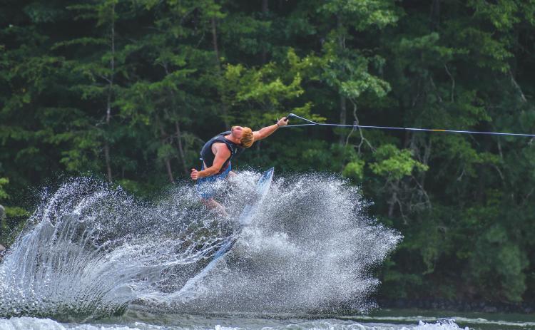 Wade Cheek/The Clayton Tribune. Chase Andrews, an original founder of the Mountain Air Classic, flies backward through the wakes of Lake Burton during his strong run at the 24th running of the lake event. Andrews and 34 other competitors did their best wakeboarding last weekend on Saturday, Aug, 3.