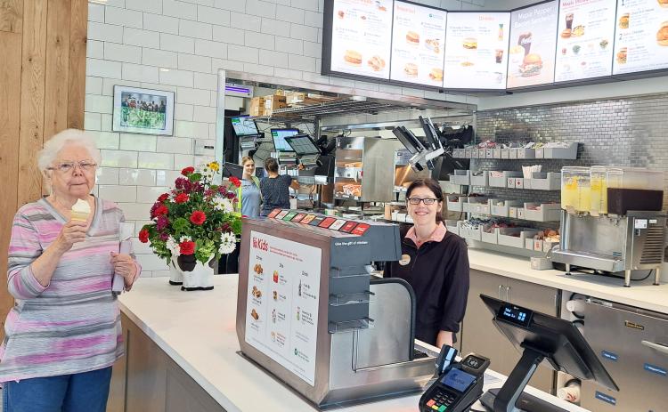 Megan Horn/The Clayton Tribune. Customer Linda Bradley with team member Kourtney. Below: Those who order from the Chick-fil-A mobile app can go through the right “mobile-thru” lane at the restaurant and scan a QR code to obtain their order.