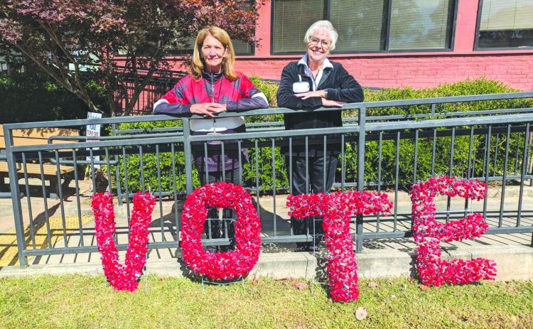 Photo courtesy of Tammy Whitmire. Rabun County Elections Office Poll Workers Kathy Allen, left, and Ann D’Agostino pose in front of this handmade sign encouraging the community to VOTE. D’Agostino made the artwork from the seals taken off of the Ballot Marking Device (BMD) every day.