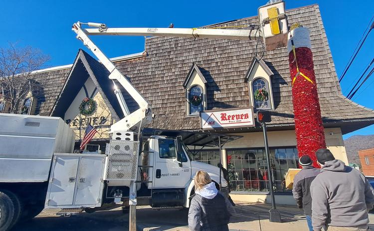 Megan Horn/The Clayton Tribune. City of Clayton workers spend hours on Monday installing the iconic candle atop Reeves at the intersection of Main Street and East Savannah Street. Santa Claus will light the candle on Saturday, Dec. 7, at the end of the parade.