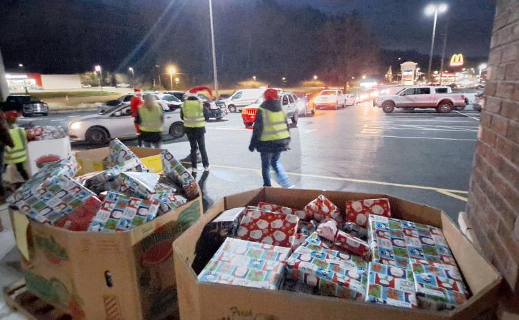 Megan Horn/The Clayton Tribune. Volunteers at the Food Bank Toy Drive prepare to hand out gifts as a row of vehicles wraps around the Food Bank parking area on Monday.