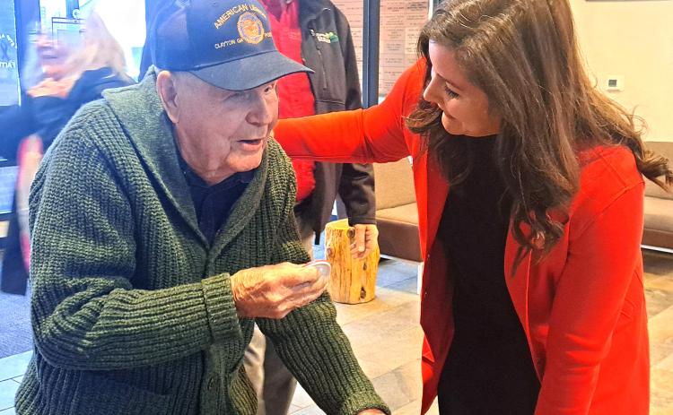 Megan Horn/The Clayton Tribune. Carolyn Culpepper with Family Hospice greets WWII U.S. Navy veteran Lt. J.G. Dr. Eldred Causey at the Vet-to-Vet Café for his 101st birthday on Feb. 11. Culpepper presented him with his button that has his motto, “Go with the Flow.”