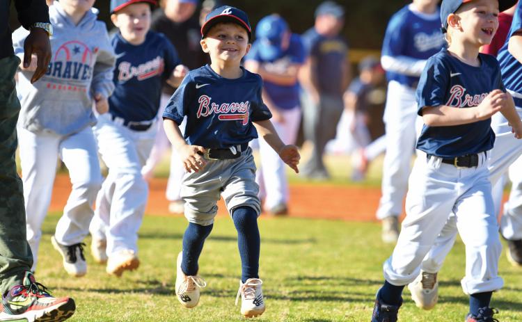Wade Cheek/The Clayton Tribune. Davis Leverette joins the rest of RCLL in running to home plate for a performance by former MLB player and musical artist CJ Beatty. RCLL held its opening day ceremony to kick off the new season.