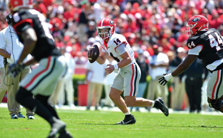 Wade Cheek/The Clayton Tribune.  Gunner Stockton evades pressure from his own Bulldog teammates in Georgia’s spring game last weekend. Stockton led his red team to a 34-17 win over the opposing black team and fellow quarterback Ryan Puglisi.