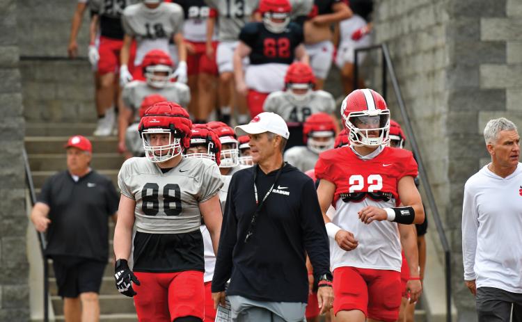 Wade Cheek/The Clayton Tribune. Seniors Ethan Hopper (left) and Ty Truelove (right) join head coach Rance Gillespie (middle) in leading the Wildcats into Frank Snyder Memorial Stadium before Rabun’s spring football game on Friday, May 16.