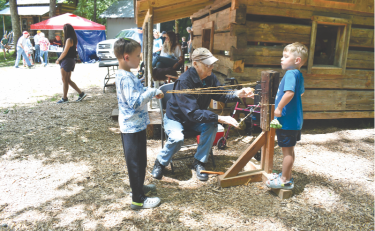 File/Megan Horn/The Clayton Tribune. Kermit Rood demonstrates rope making to youngsters Archer Reinhardt, 8; and Brandt Reinhardt, 6, at last year’s Foxfire Heritage Days event.