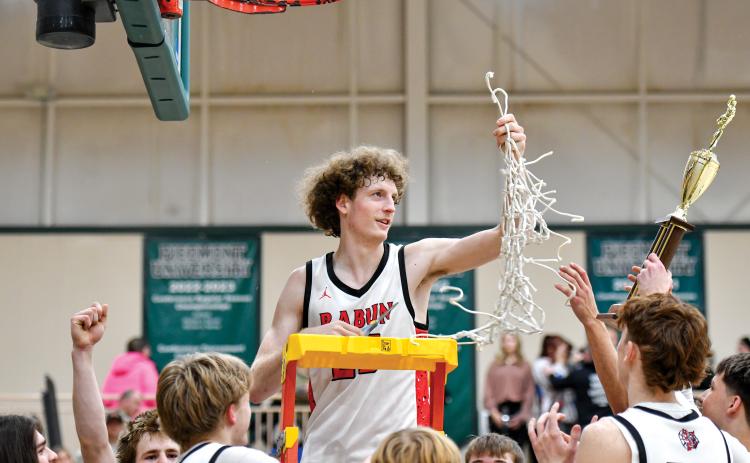 Wade Cheek/The Clayton Tribune. Rabun County post Hayes Free hoists up the net after the Wildcats won the 8A-DI region title over Commerce High School last season.