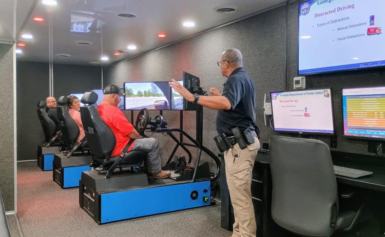 Megan Horn/The Clayton Tribune. Officer Hammock with the Georgia Department of Public Safety Motor Carrier Compliance Division instructs Transportation Department employees on driver education safety with a driving simulator. Rabun County Schools held its back to school meeting on July 29 at the Rabun County Board of Education.