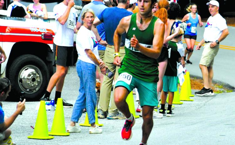Enoch Autry/The Clayton Tribune. Ben Perrin crosses the finish line as the first overall male in the Rabun Ramble 10K.