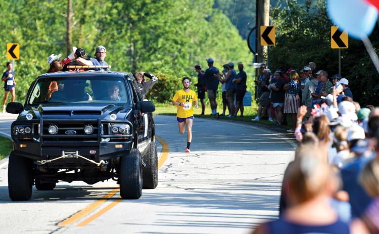 Wade Cheek/The Clayton Tribune. Led by the pace car, Nolan Weisdorfer sprints toward the finish line to repeat as the overall winner of the Lake Burton Fun Run on Saturday, July 5.