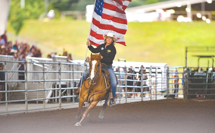 Wade Cheek/The Clayton Tribune. Jamie Ellsworth rides through Rabun Arena with the Stars and Stripes during the opening ceremonies of the Rabun Arena Rodeo 2024 Fourth of July weekend.