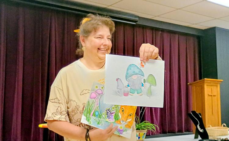 Megan Horn/The Clayton Tribune.  Gretchen Roach displayed her mixed-medium illustrations featuring fairies and gnomes during the Guild’s “Members’ Show and Tell” program July 17. She said her focus is to produce something positive in her creations.