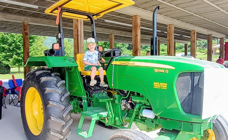 Megan Horn/The Clayton Tribune. Declan Alexander, 4, has fun playing on this farm tractor presented by Marty Franklin during the Aug. 16 “Touch-A-Truck” event. The family-friendly event allowed kids with their families to climb, “touch,” and explore many vehicles that represent our community heroes.