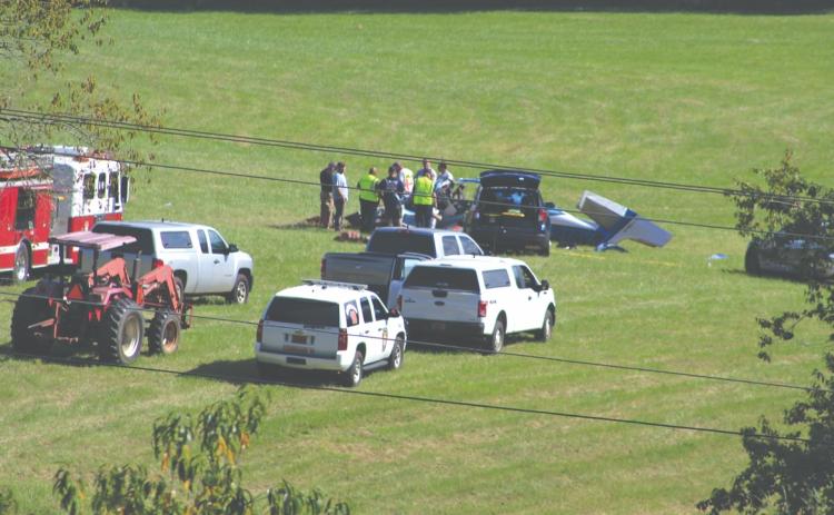 Shelby Powell/CNI News Service. Emergency personnel respond to a plane crash Thursday afternoon in a field west of Iotla Valley Elementary School. The three people aboard were killed.