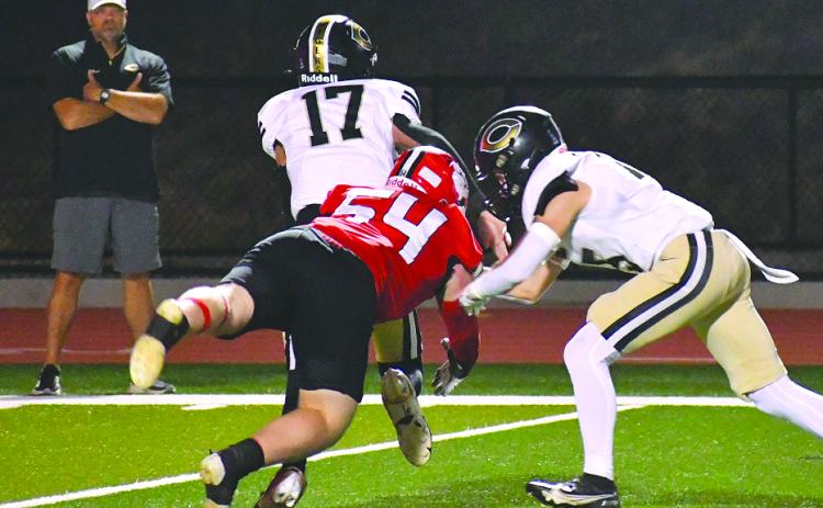 Enoch Autry/The Clayton Tribune. Commerce City School System Superintendent Billy Kirk (far left) watches as Wildcat Ryan Yearwood makes a hit on Commerce quarterback Tate Kirk, the superintendent’s son. The elder Kirk would be ejected from the game in the third quarter. RCHS won 55-28.