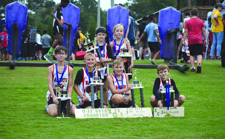 Submitted Photo. Rabun County high-point top-five champions are Caiden Wood, Kai Hanifan-Wagner, Owen Mosely, Keegan Hanifan-Wagner, Nora Webb and Opal Aker sit on the grass with their trophies at the concluson of the district championship at Athens Christian School.