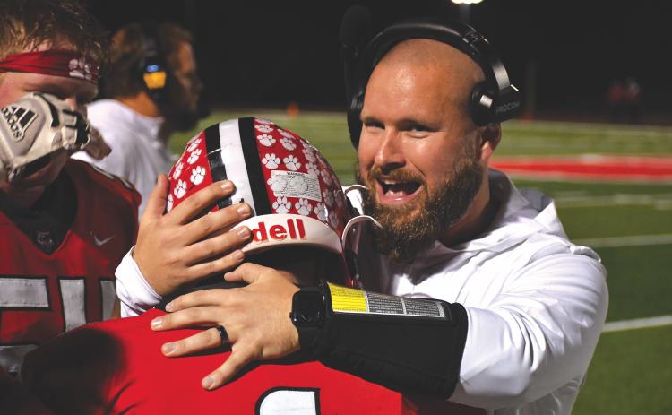 Wesley Branch/The Clayton Tribune. Rabun County running backs coach Clay Worley hugs Lake Evans after the senior dashes down the visitors’ sideline for a 46-yard touchdown on Nov. 21. The Wildcats head to Pepperell for the Elite Eight Friday.