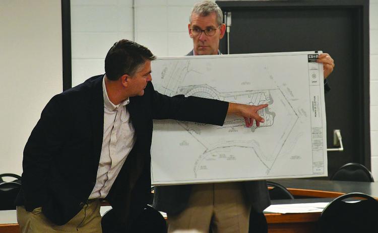 Enoch Autry/The Clayton Tribune. With Gary Hammond Jr., developer/owner of Landbridge Development holding the rendering, Matt Kriete of Engineering, Survey and Services, Inc., points out the location where the parking spots would go on the property at the future Peaks of Clayton housing project.