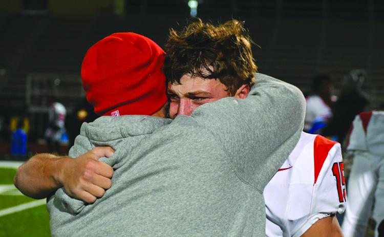Enoch Autry/The Clayton Tribune. Rabun County senior Reid Giles sheds a tear during a hug with assistant coach Clay Worley on the field after the Wildcats lose to Pepperell in the Elite Eight in Lindale the day after Thanksgiving.