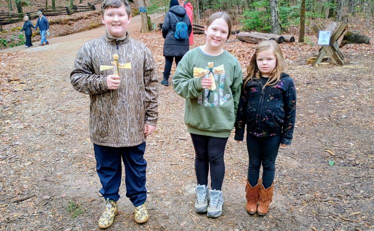 Megan Horn/The Clayton Tribune. Bentley Conner, 10; Ava Conner, 9; and Harper Mashburn, 6, enjoy their time at “A Foxfire Christmas” last weekend. The kids are holding corn husk dolls, one of many crafts made during the event.