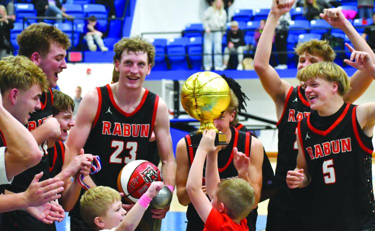 Wesley Branch/The Clayton Tribune. Reeves Page hoists the Battle of the States championship trophy while he and Cal Burrell (left center) celebrate with the Rabun County boys basketball team on Dec. 30 after its 64-59 win over Chesnee. The Wildcats will be at home again on Jan. 13 versus Athens Academy.
