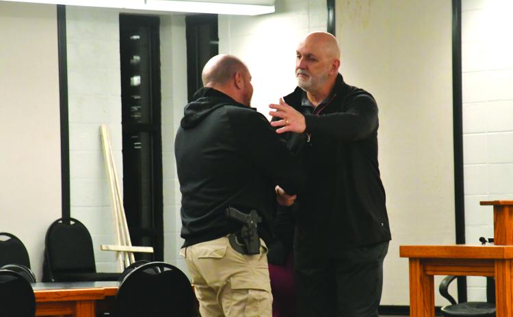 Enoch Autry/The Clayton Tribune. Retiring Clayton Police Chief Andy Strait shakes the hand of new city council member Channing Watts at the conclusion of Tuesday night’s meeting. Colt Woodall (far left) and Mayor Pro Tem Stacy Fountain watch..