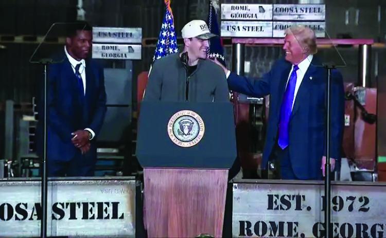 Video image/Fox5 Atlanta. Rabun County standout and current Georgia quarterback Gunner Stockton is greeted at the podium in Rome, Ga., on Feb. 19 by President Donald Trump. Standing with Stockton and Trump is Herschel Walker, Bulldog great and current ambassador to The Bahamas.
