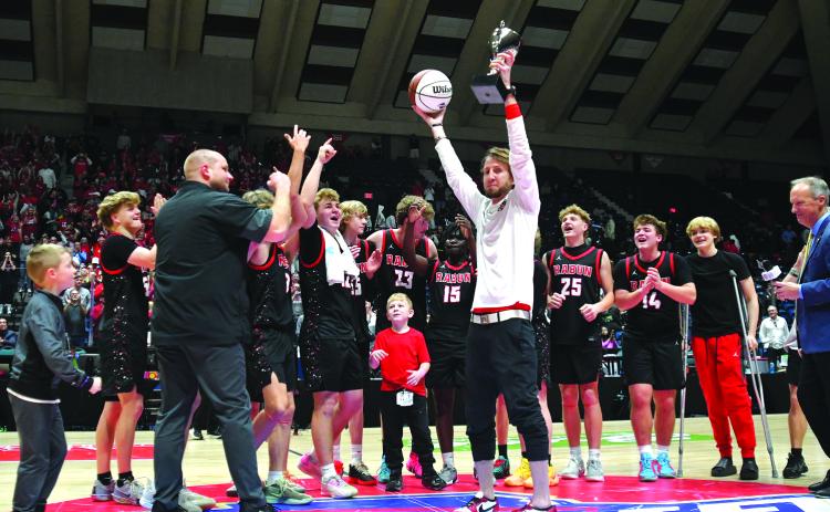 Enoch Autry/The Clayton Tribune. The Rabun County boys basketball team is the Class A Division I state champions for 2026 after capturing the title on March 13 in the Macon Coliseum with a 52-43 victory over Southwest for the first boys hoops championship in the school's history. Here Rabun County head coach David Adcock hoists the trophy and game ball into the air for his team and the crowd to see at midcourt following the triumph.