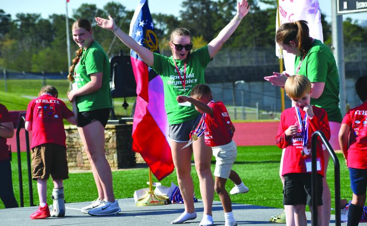 Wesley Branch/The Clayton Tribune. Adrian Appleby (center) dances on the stage with buddy and Rabun County High School student Bella Hulsey after receiving a medal at the Rabun County Special Olympics on April 2 at Frank Snyder Memorial Stadium. Also on the stage receiving medals as photographed above are athletes Truett Beck (right) and Jonathan Chapman (left) with buddies Katelynn Duncan and Chloe Shirley.
