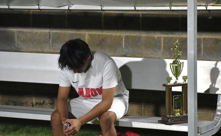Wesley Branch/The Clayton Tribune. Rabun County sophomore Alan Lozada sits on the bench in disbelief after the Wildcats’ loss in PKs to Athens Academy on April 15. Next to Lozada is the region runner-up trophy, which the Wildcats claimed for the second straight year.