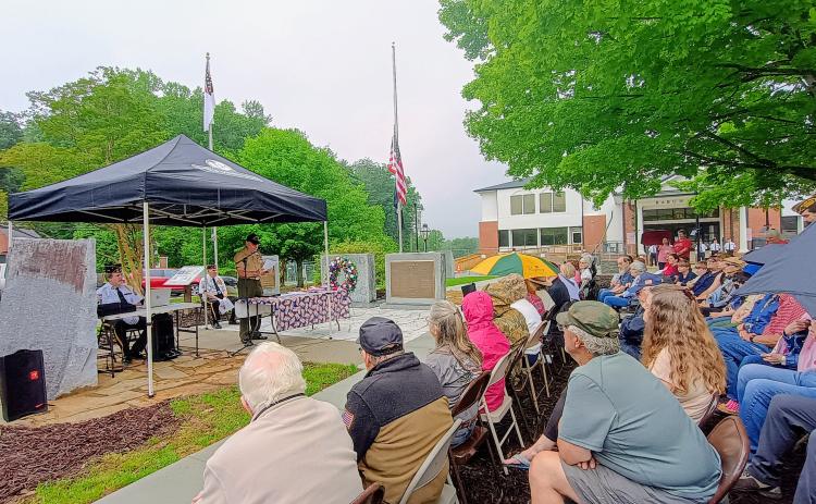 Megan Horn/The Clayton Tribune. Veteran Bruce Gant, left and center under the tent, speaks to a large crowd of community members during the May 25 Memorial Day ceremony held in front of the Rabun County Courthouse. Pictured on either side of Gant are Capt. Chris DiNofrio, U.S. Marine Corps, and Major (Ret.) Doug Wayne, U.S. Army. Gant was this year’s special guest speaker. He was a Navy Corpsman from September 1965 to September 1971. He is a Vietnam Combat veteran and two-time Purple Heart recipient. 