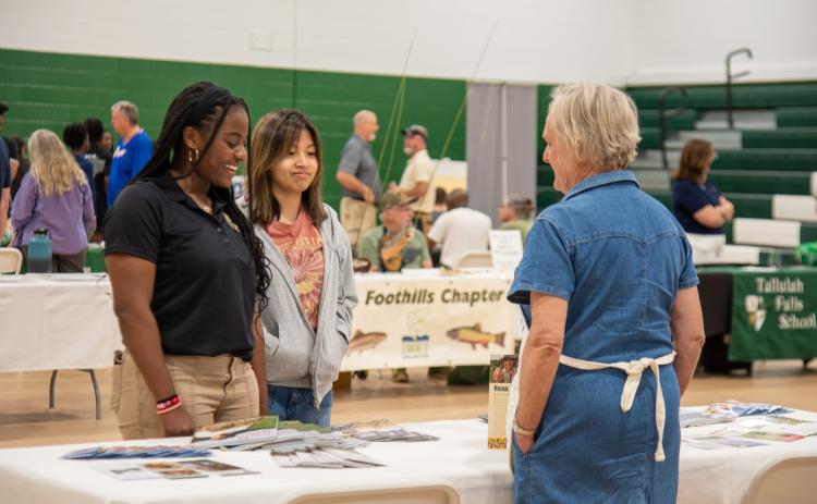 Photo courtesy Elisha Boggs.  TFS students Kaylin Pickett and Jessica Cook visit with the exhibitor at the Rabun County, Georgia Extension Office, where they picked up wildflower seeds to plant at home.