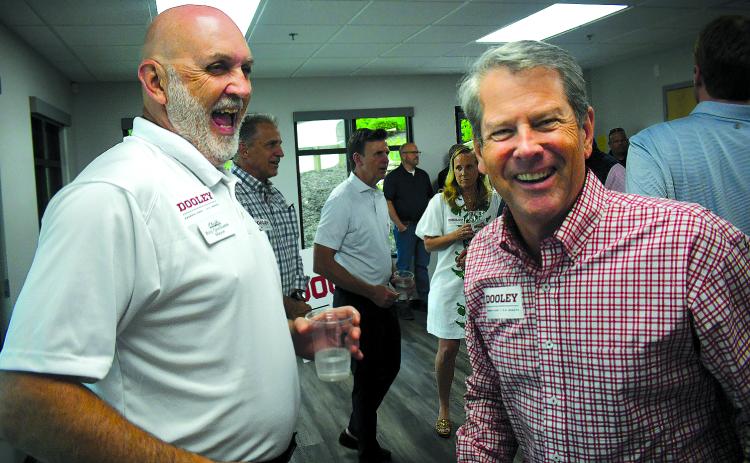 Enoch Autry/The Clayton Tribune. Clayton Mayor Roy Quilliams shares a laugh with Gov. Brian Kemp after the governor puts a Dooley for U.S. Senate sticker on Quilliams’ shirt at the May 29 Meet & Greet in Rabun County.