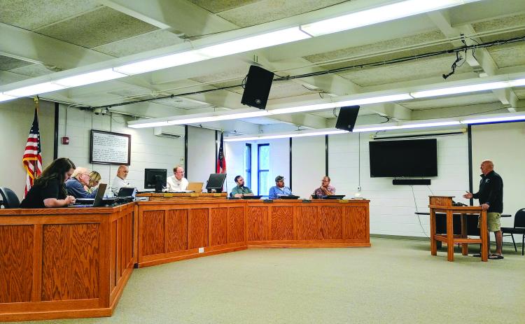 Megan Horn/The Clayton Tribune. Moonrise Distillery owner Doug Nassaur, far right, talks to Clayton City Council members on July 14 about delinquent taxes reported by the city. Nassaur addresses (from left) City Manager Kessiah Gipson, Council Member Tony Allen, City Manager Trudy Crunkleton, Mayor Roy Quilliams, City Attorney Mitch Baker, and council members Colt Woodall, Channing Watts and Stacy Fountain. 