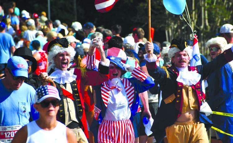Wesley Branch/The Clayton Tribune. Several participants of the Lake Burton Fun Run showed their patriotism by wearing red, white and blue, or by dressing up in costumes like the trio celebrating here as they cross the finish line. Despite the warm temperatures, thousands were in attendance on July 4 for the 42nd annual Lake Burton Fun Run from Moccasin Creek State Park to LaPrade’s Marina. 