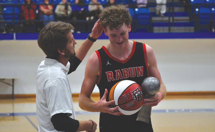Wesley Branch/The Clayton Tribune. Rabun County head boys basketball coach David Adcock (left) presents RCHS senior Hayes Free with a commemorative ball for scoring his 1,000th career point after the Wildcats’ win over Chesnee (S.C.) on Dec. 30. Free recently announced his commitment to Young Harris College.