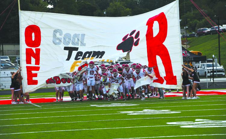 Enoch Autry/The Clayton Tribune. Rabun County football players break through the cheerleaders’ handmade banner on Aug. 14 prior to the Wildcats’ scrimmage on the road against Franklin, N.C. RCHS kicks off its regular season at home on Aug. 28 versus the Tigers of Metter, led by former Wildcat coach and player Lee Shaw.