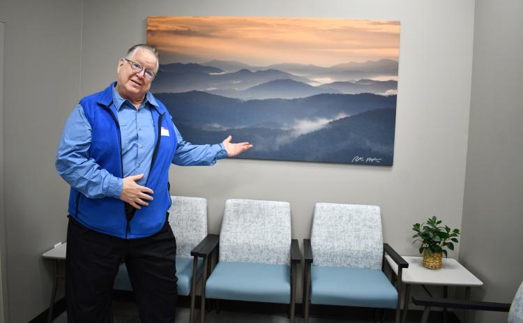Megan Horn/The Clayton Tribune. Local photographer Peter McIntosh has 16 large pieces on display at MedLink Georgia Rabun Health Campus and hand-signed all of them. Here, he is pictured March 26 in front of his photograph capturing a view from Tennessee Rock Overlook at Black Rock Mountain State Park. McIntosh passed away on July 20. 